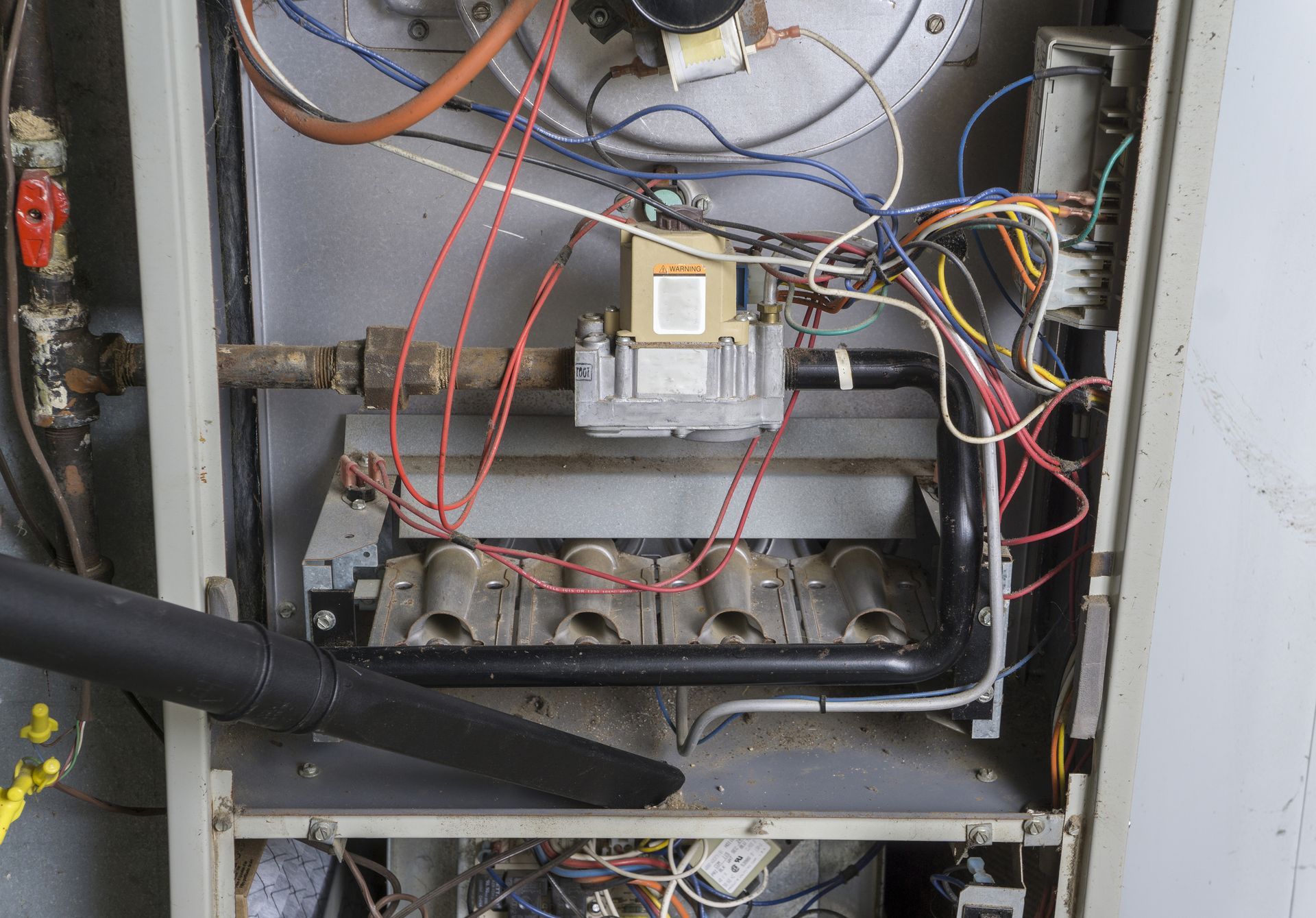 A person is cleaning a gas heater with a vacuum cleaner.
