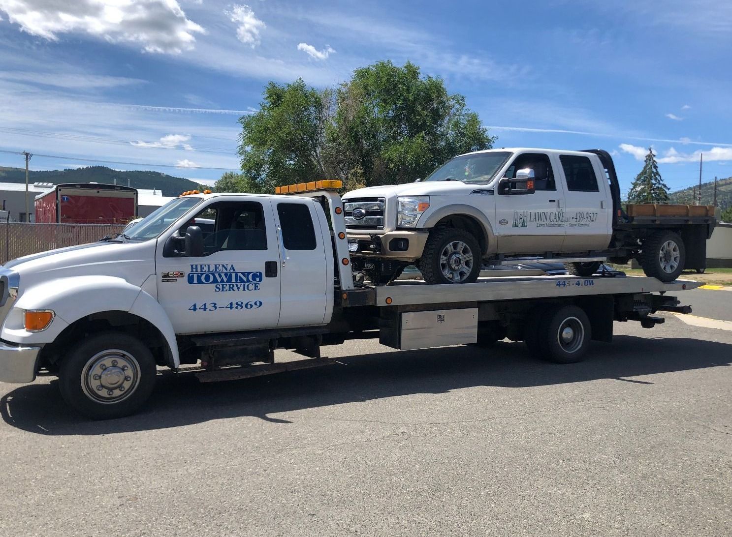 Two trucks are sitting on top of a tow truck.