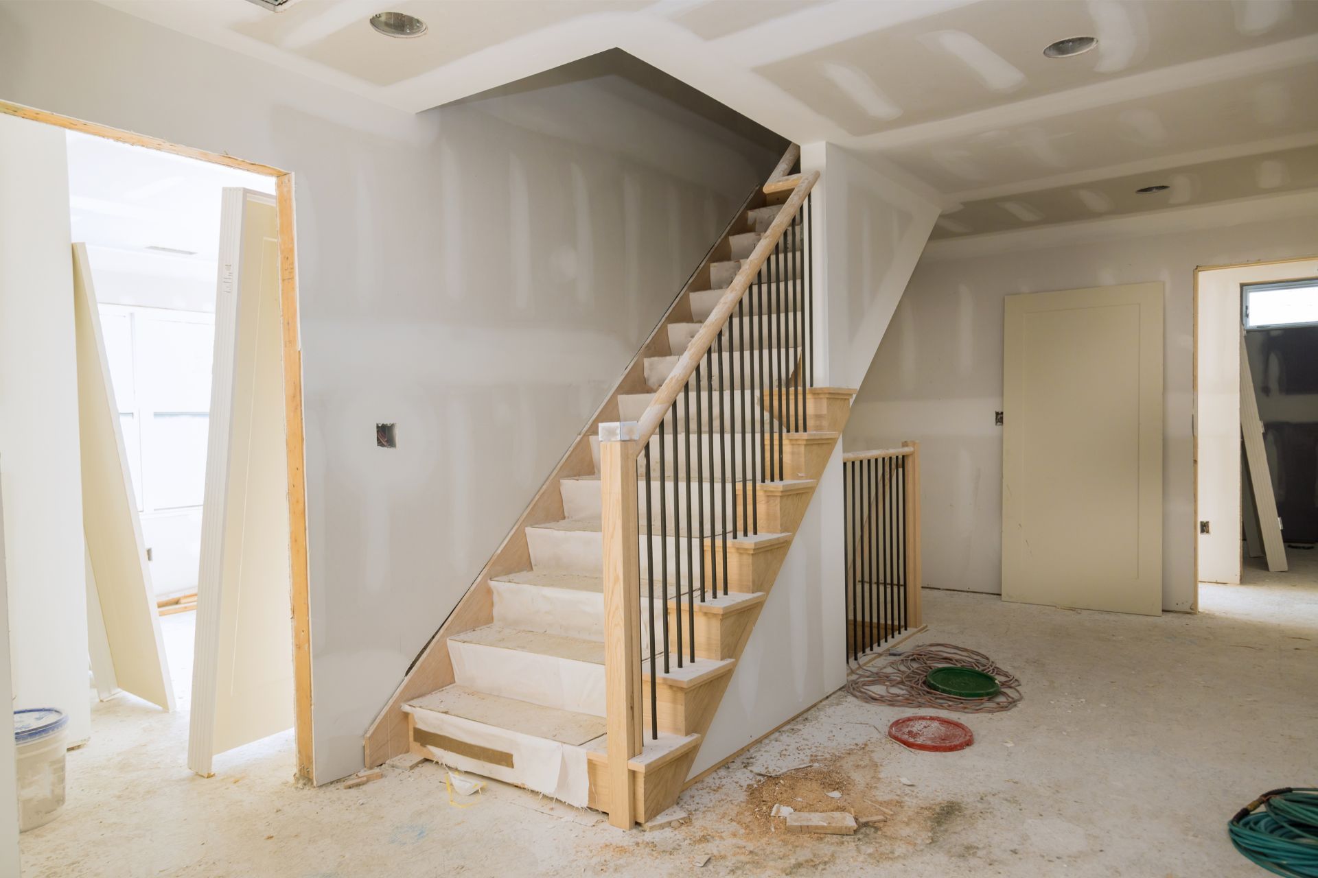 Under-construction staircase with metal balusters in a primed room.