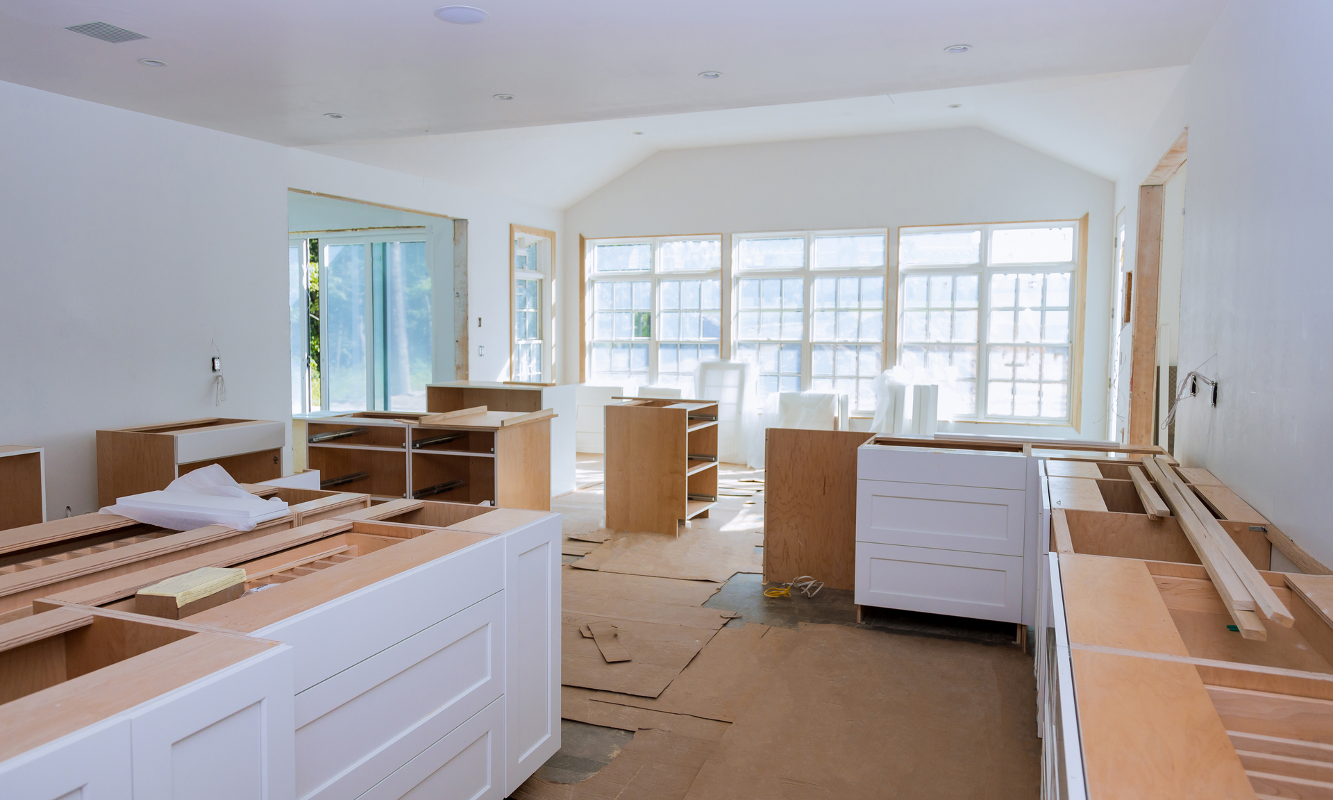 a photo of an open kitchen and living room remodeling project. the rooms are pretty much empty. the cabinetry is there but has not been installed yet.