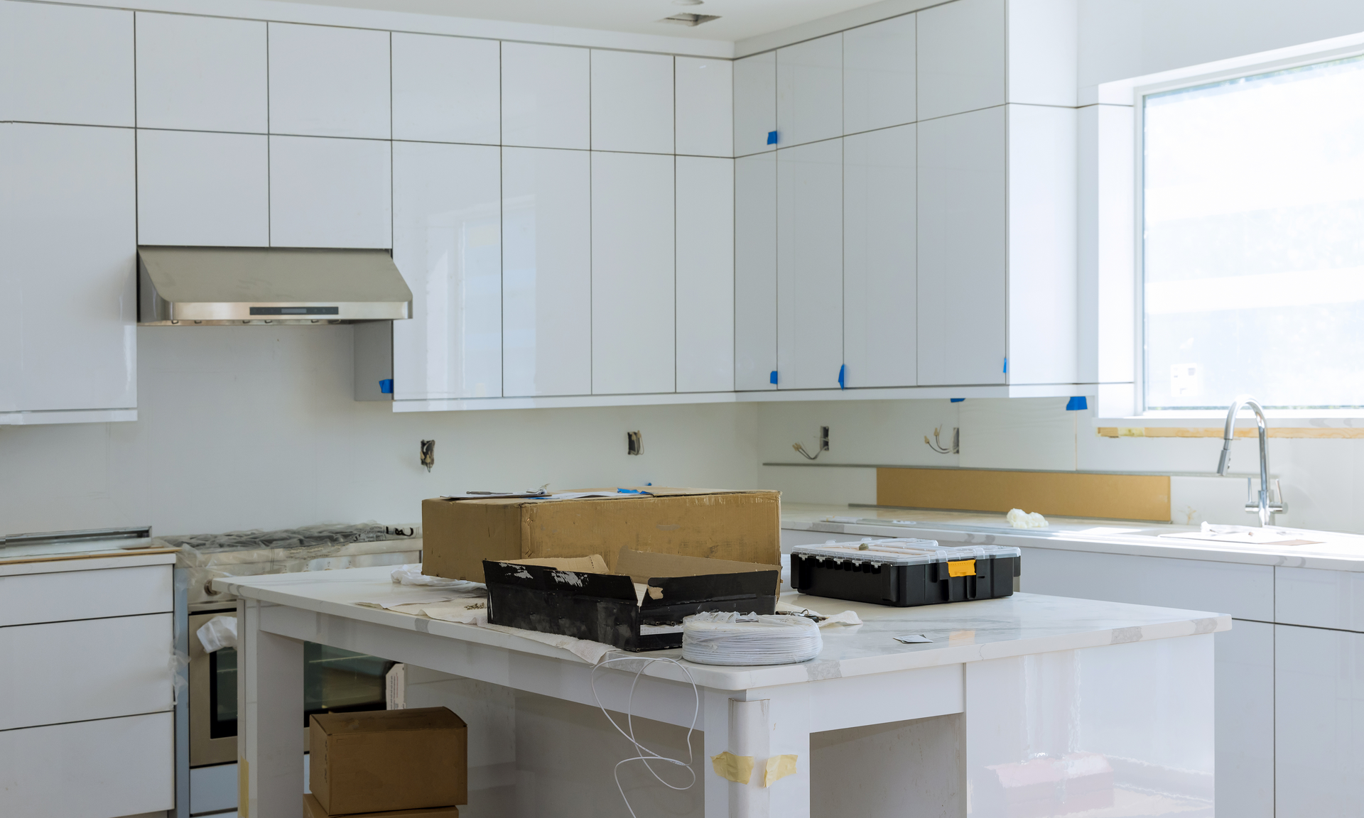a modern kitchen being remodeled with sleek white cabinets and grey granite countertops