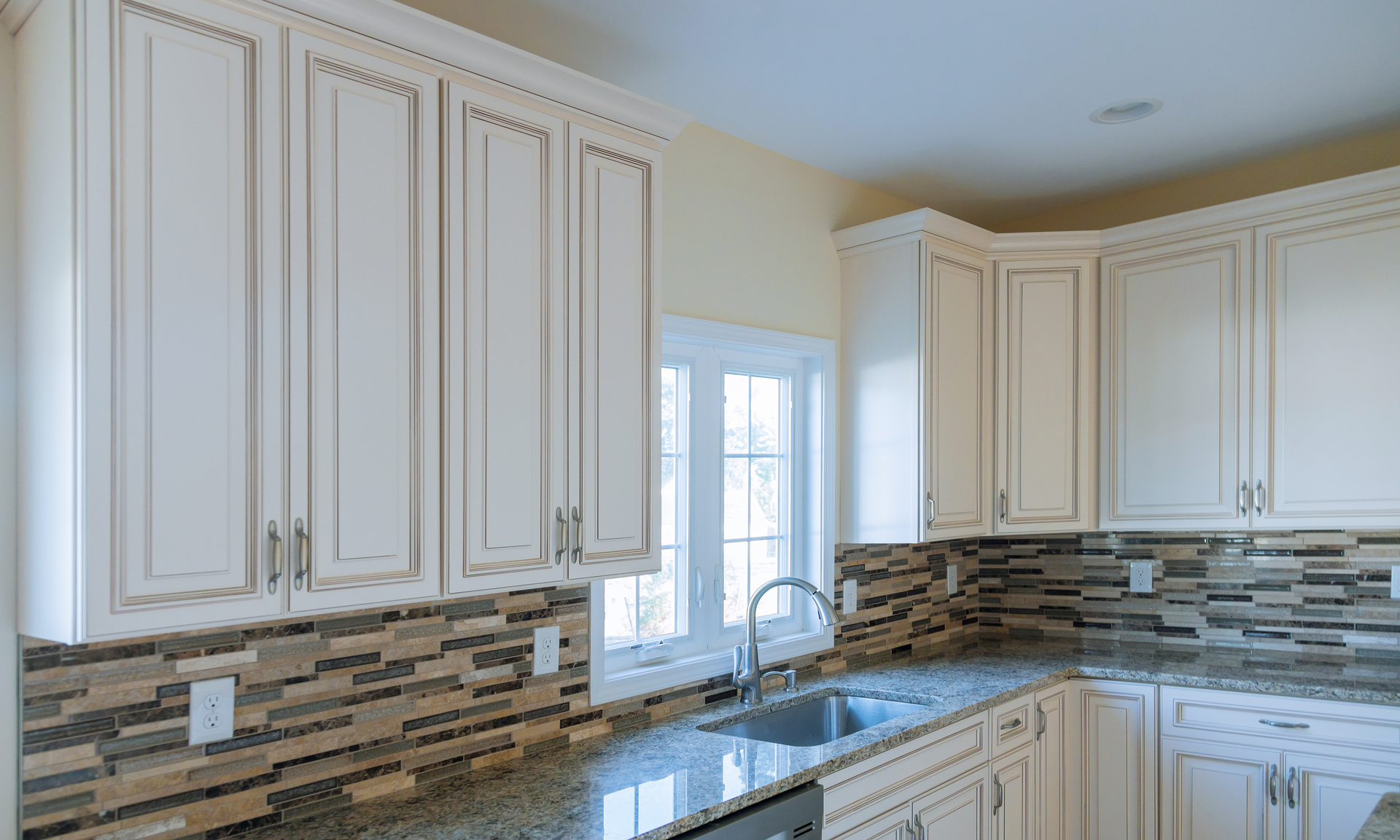 a photo of a finished kitchen remodeling project with dark granite countertops and white cabinetry
