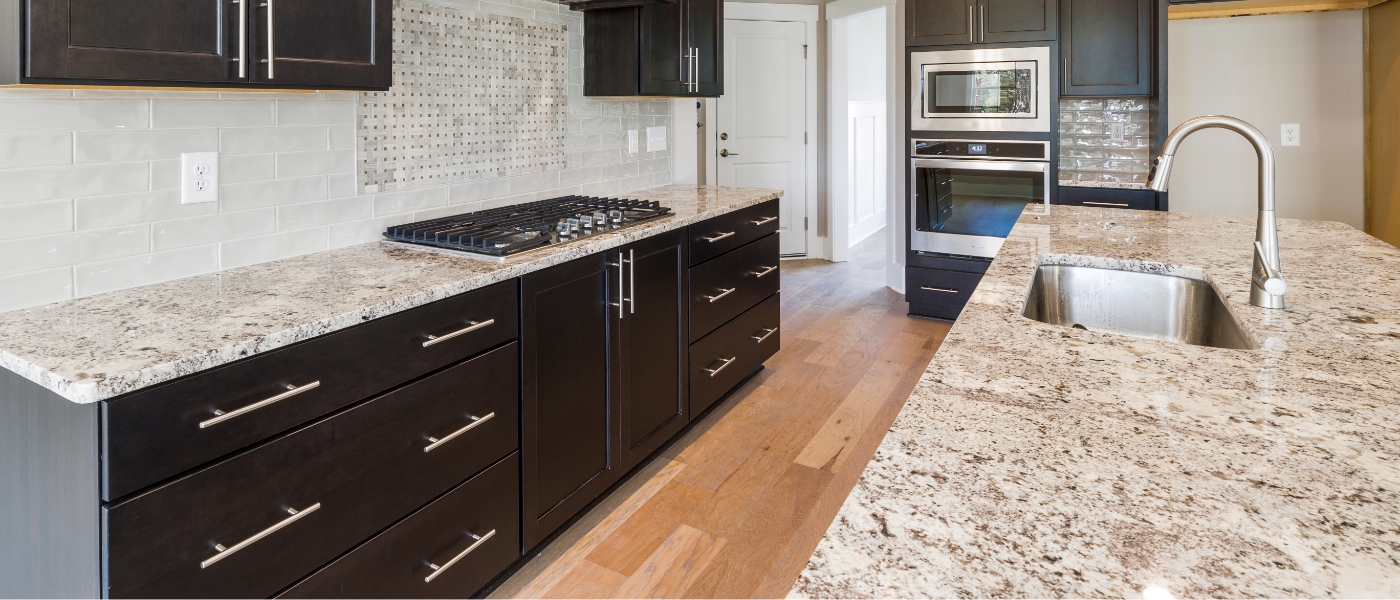Photo of beautiful granite kitchen countertops coupled with dark brown kitchen cabinets and brushed steel appliances. 
