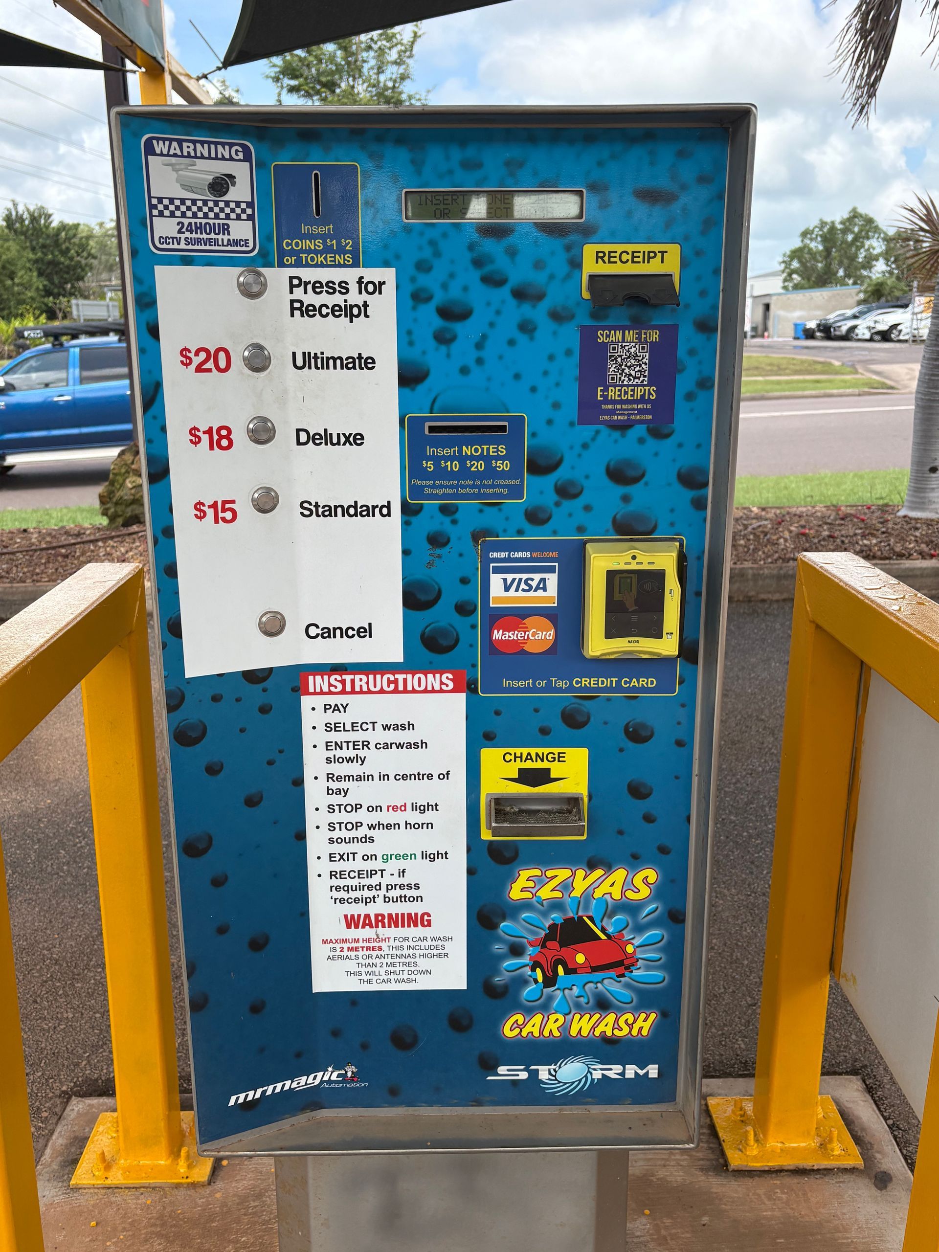 Blue car wash payment kiosk with instructions, coin slot, and card reader outdoors — Ezyas Car Wash NT in Yarrawonga, NT