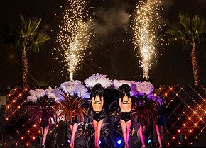 A group of women are standing on a stage in front of fireworks.