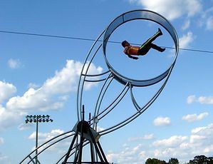 A man is flying through a circle on a ferris wheel.