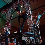 Circus performers on a rotating platform, balancing, and riding bicycles.