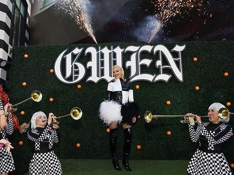 Gwen Stefani poses on stage in black and white, with trumpeters;