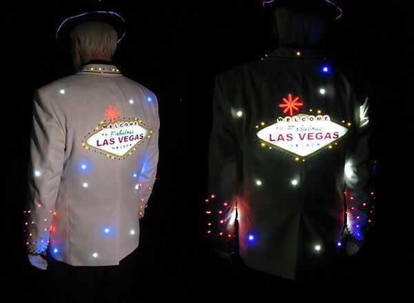 Two men in light-up jackets with Las Vegas sign on the back, lit up with colorful LEDs.