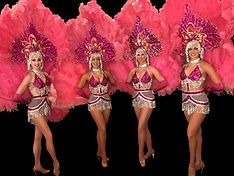 Four showgirls in pink feathered headdresses and costumes pose against a black backdrop.