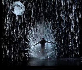 A man is standing in the rain with a full moon in the background.