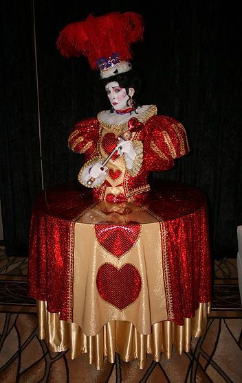 Costume of the Queen of Hearts, featuring red and gold bodice and table-like skirt.