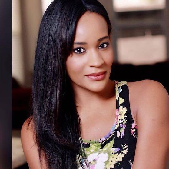 Woman with long dark hair and a floral top smiles at the camera.