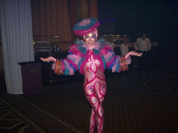 Person in colorful body paint and costume poses at an event.