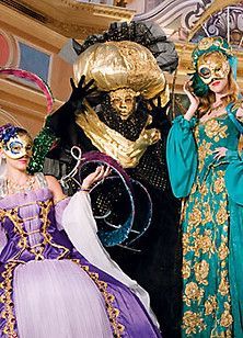 Three women wearing masks and costumes are standing next to each other.