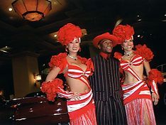 Floyd Mayweather poses with two women in red and white outfits.