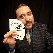 Man in suit holding cards with symbols, dark background.