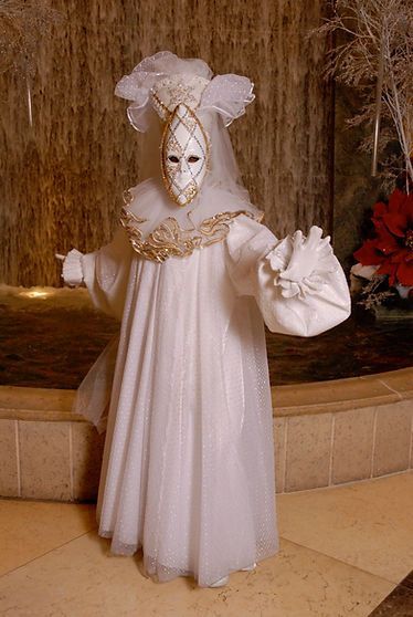 Person in white costume and mask, standing in front of a waterfall.