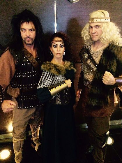 Three people in Viking costumes: a woman in the center, flanked by two men. They are posing with fists up.