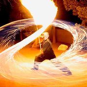 Person in martial arts stance, wielding glowing sword, surrounded by swirling fire and energy.