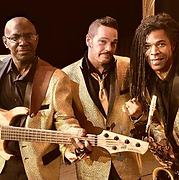 Three musicians in gold jackets, posing, playing instruments: bass guitar, saxophone.