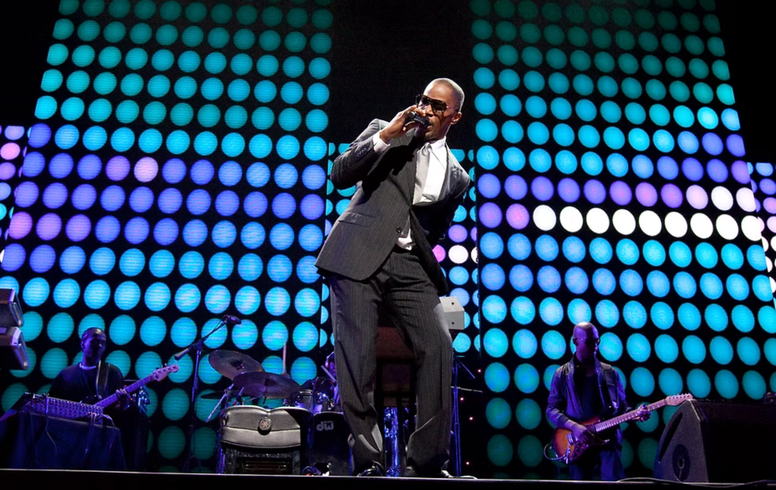 A man in a suit is singing into a microphone on a stage