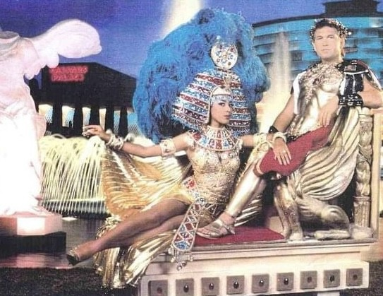Two costumed performers, Cleopatra and Caesar, pose in front of a classical setting.