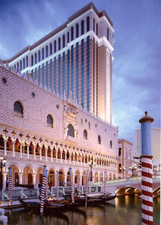 The Venetian hotel in Las Vegas. A canal with gondolas in front of a building, with a tall tower.