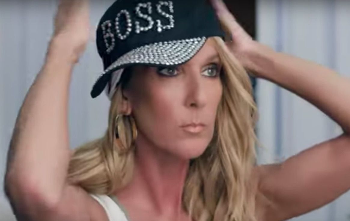 Celine Dion putting on a black baseball cap with 