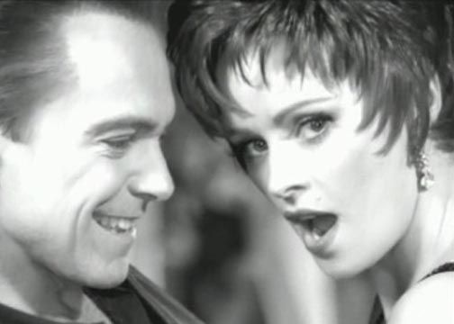Smiling man and woman with surprised expression, close-up in black and white.