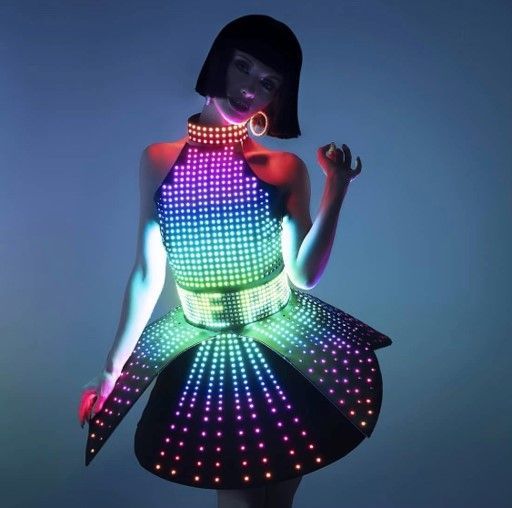 Woman in a glowing LED dress and collar, posing with a hand up.
