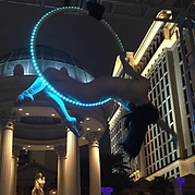 Aerialist performing in a lit-up hoop. Las Vegas, blue lights, acrobatic pose.