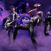 Rock band onstage, performing. Purple stage lighting, band logo on drums. Singer passionately singing.