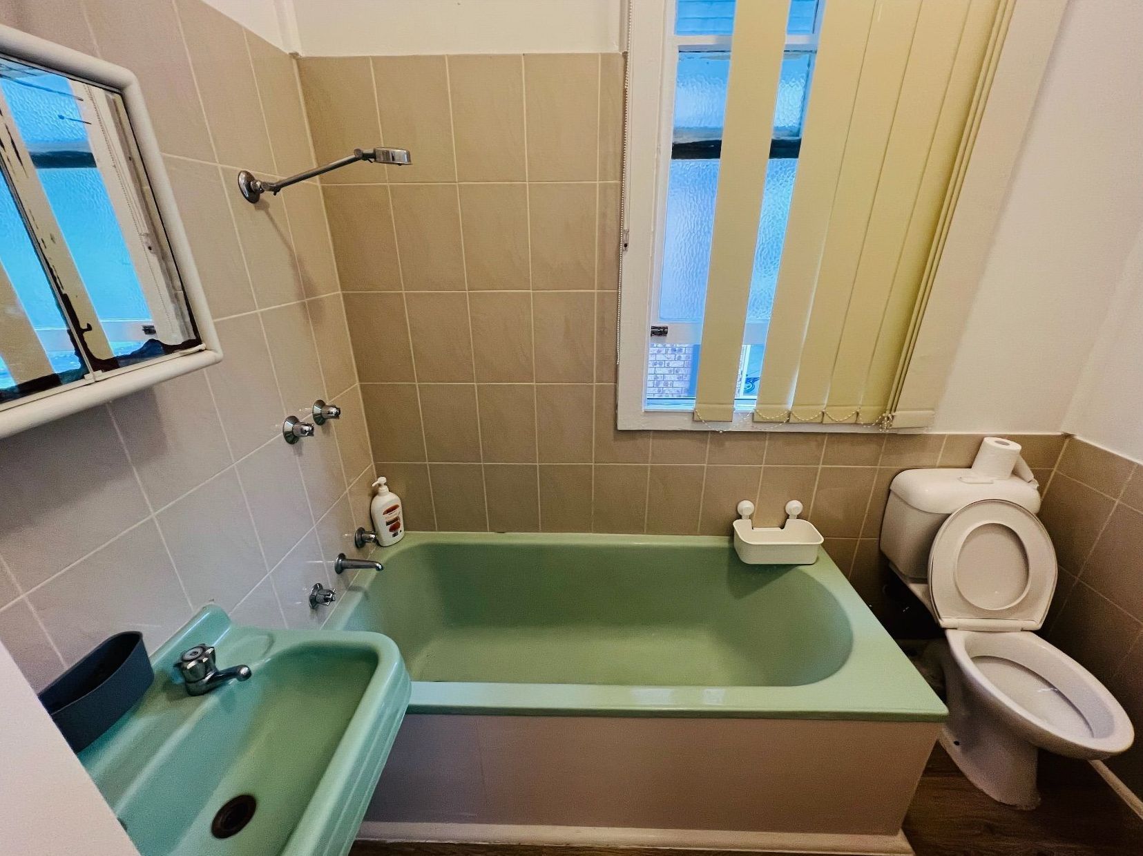 A bathroom with green tiles and a toilet and sink