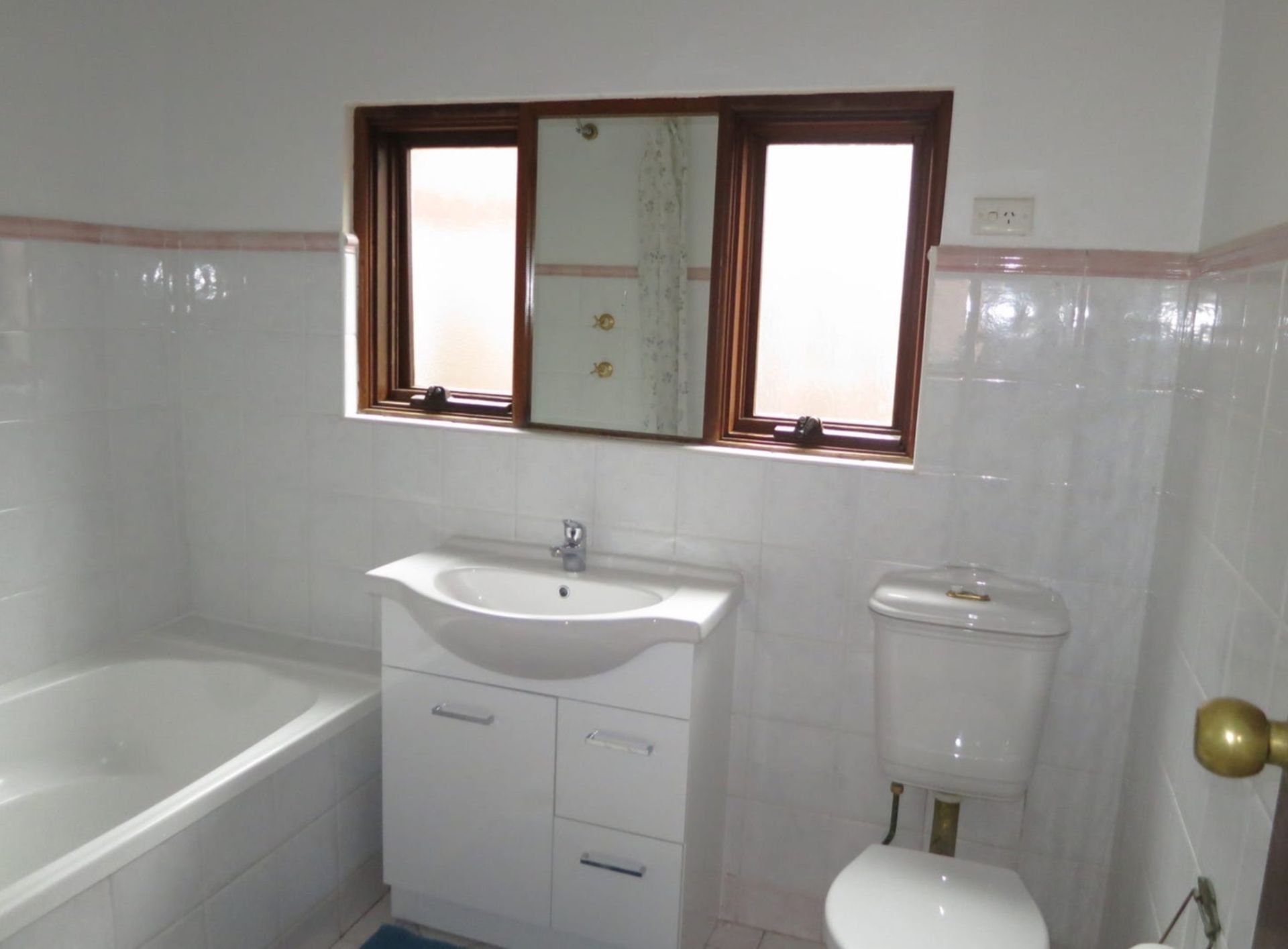 A bathroom with green tiles and a toilet and sink