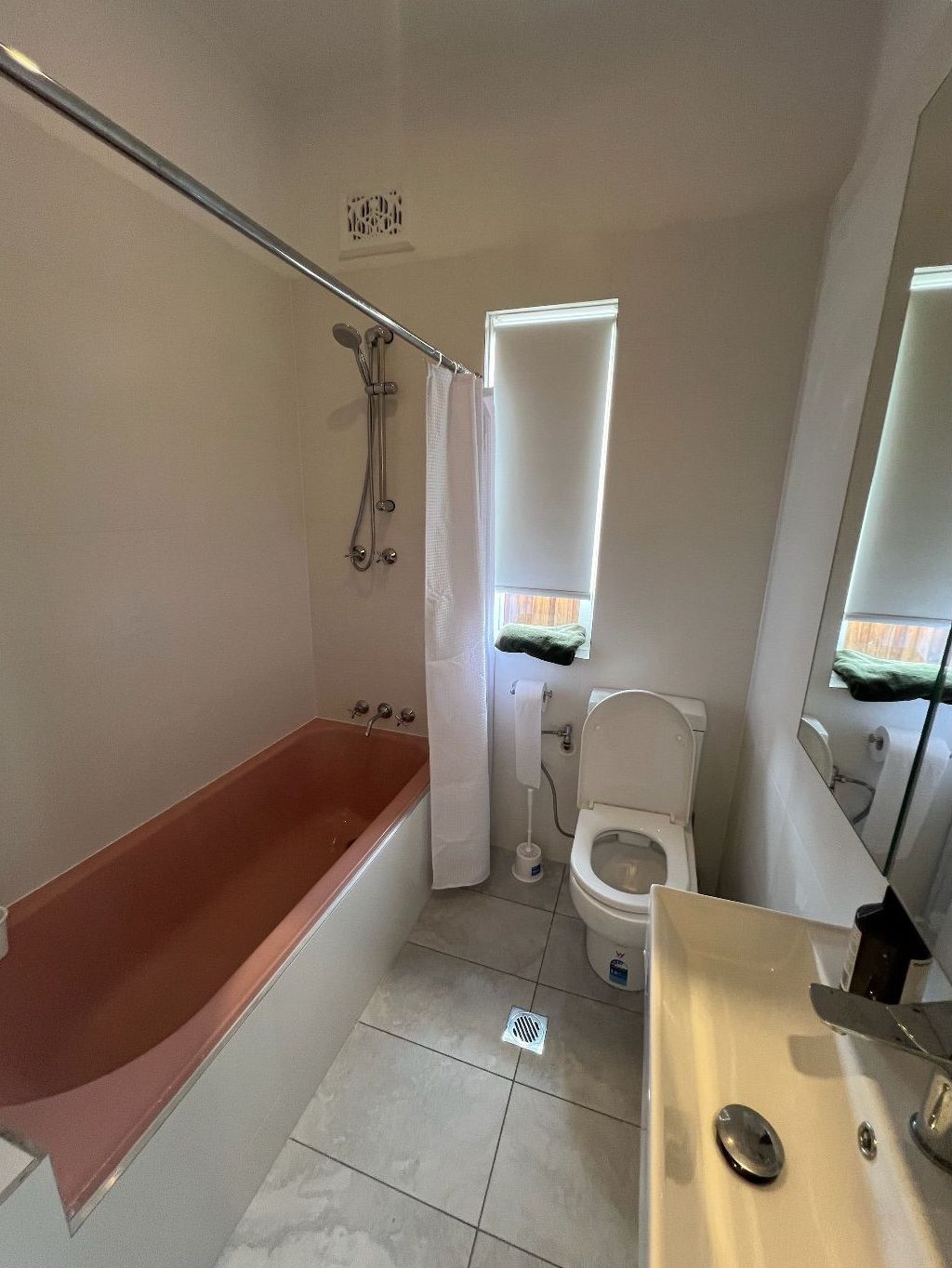 A bathroom with green tiles and a toilet and sink