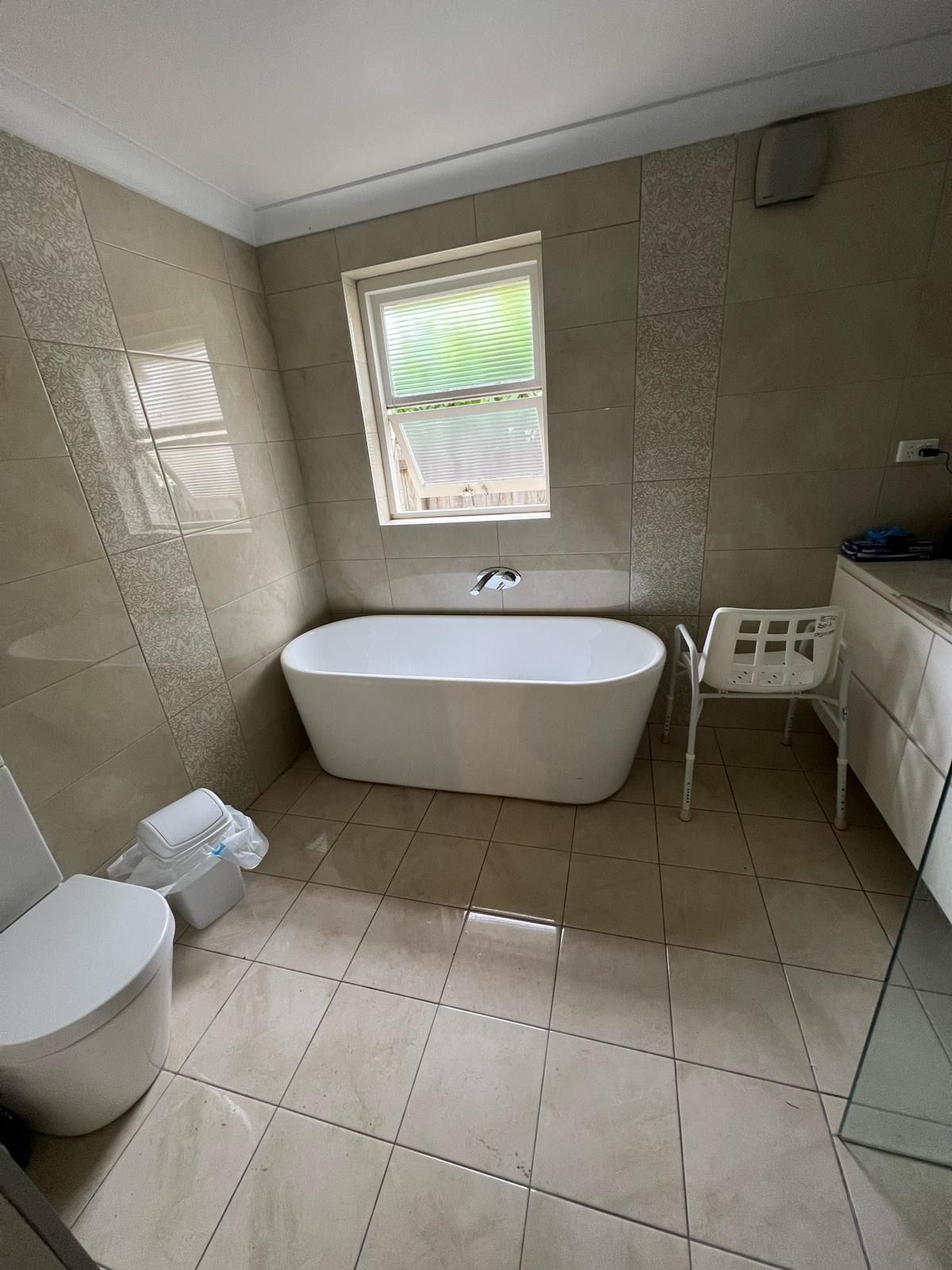 A bathroom with green tiles and a toilet and sink