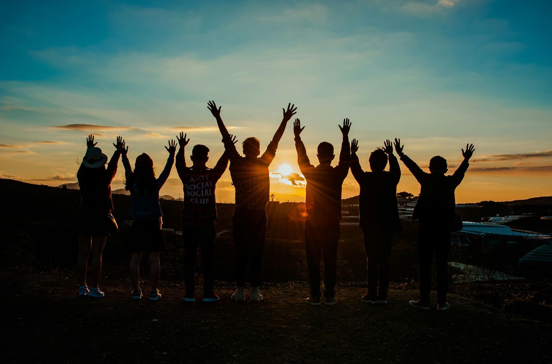A group of people are standing next to each other with their arms in the air.
