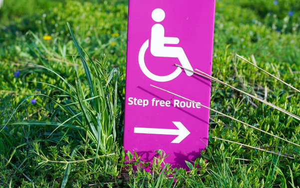 A woman in a wheelchair is sitting in front of a bush.