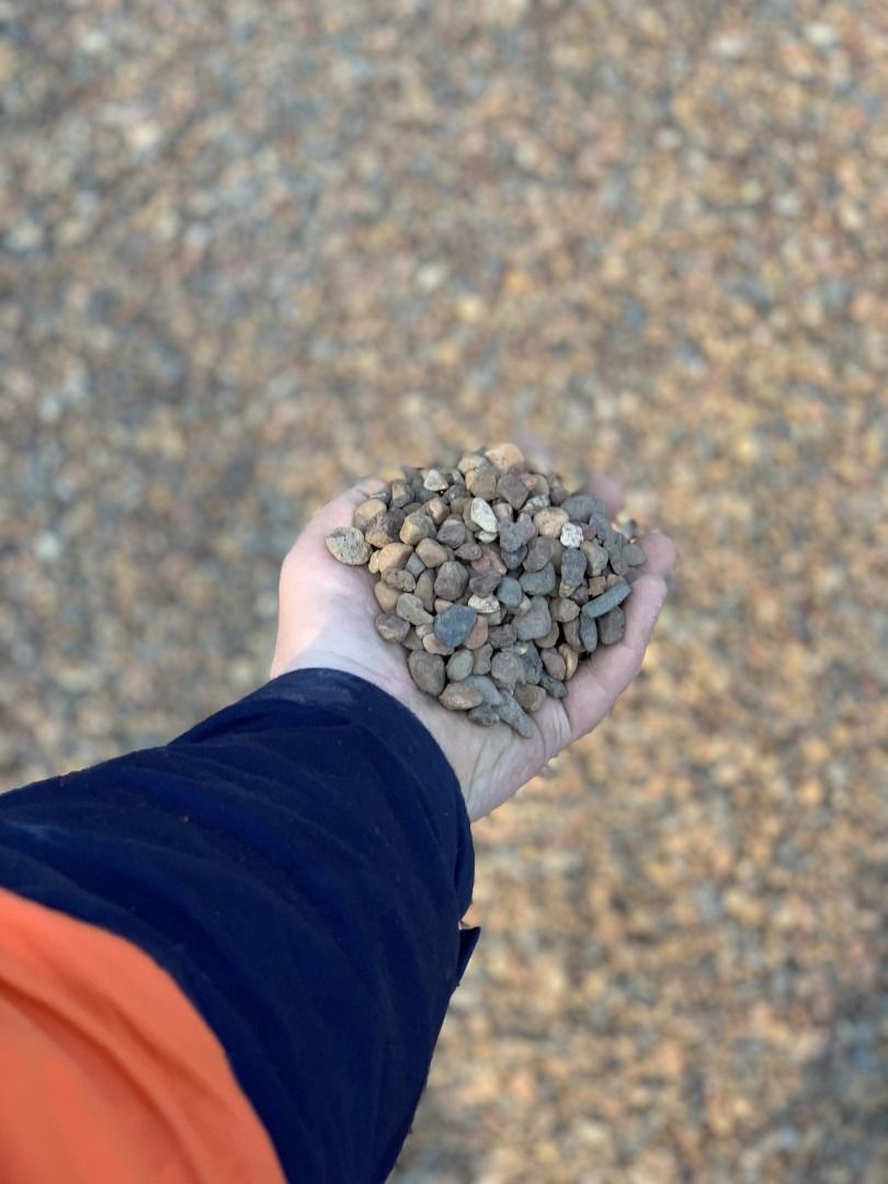 A Person Is Holding A Pile Of Gravel In Their Hand — Serious About Landscape Supplies In West Gosford, NSW