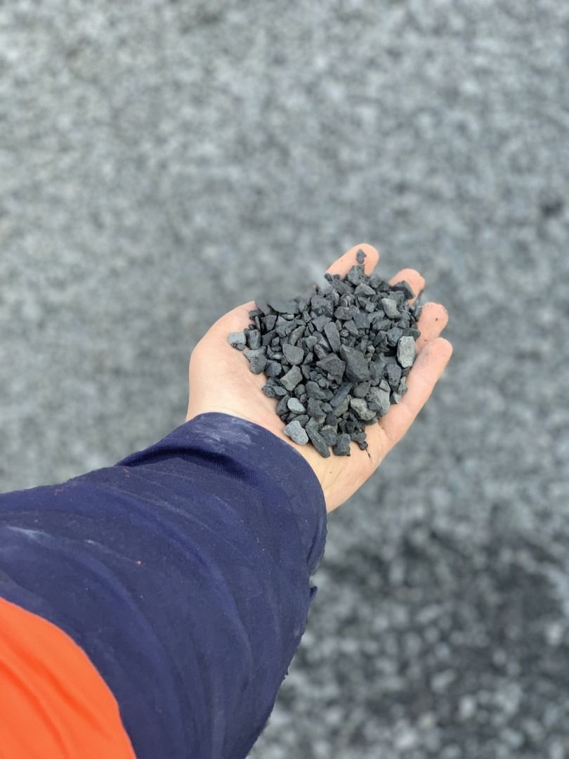 A Person Is Holding A Pile Of Gravel In Their Hand — Serious About Landscape Supplies In West Gosford, NSW