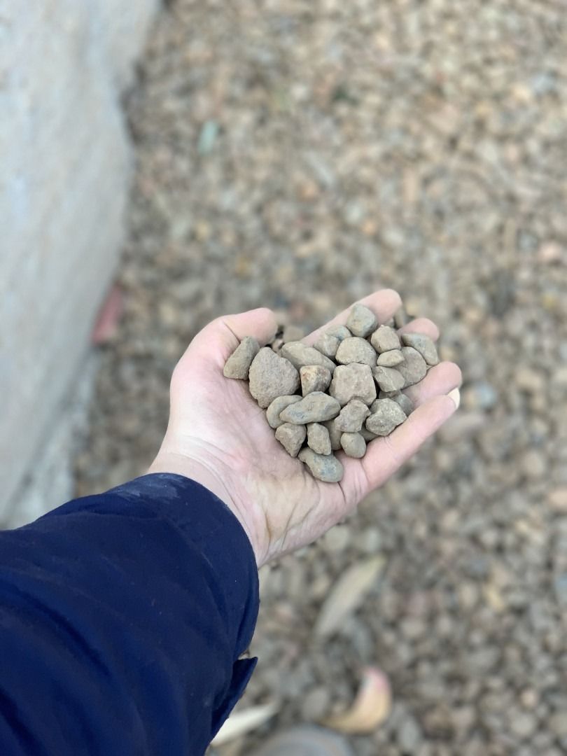 A Person Is Holding A Pile Of Rocks In Their Hand — Serious About Landscape Supplies In West Gosford, NSW