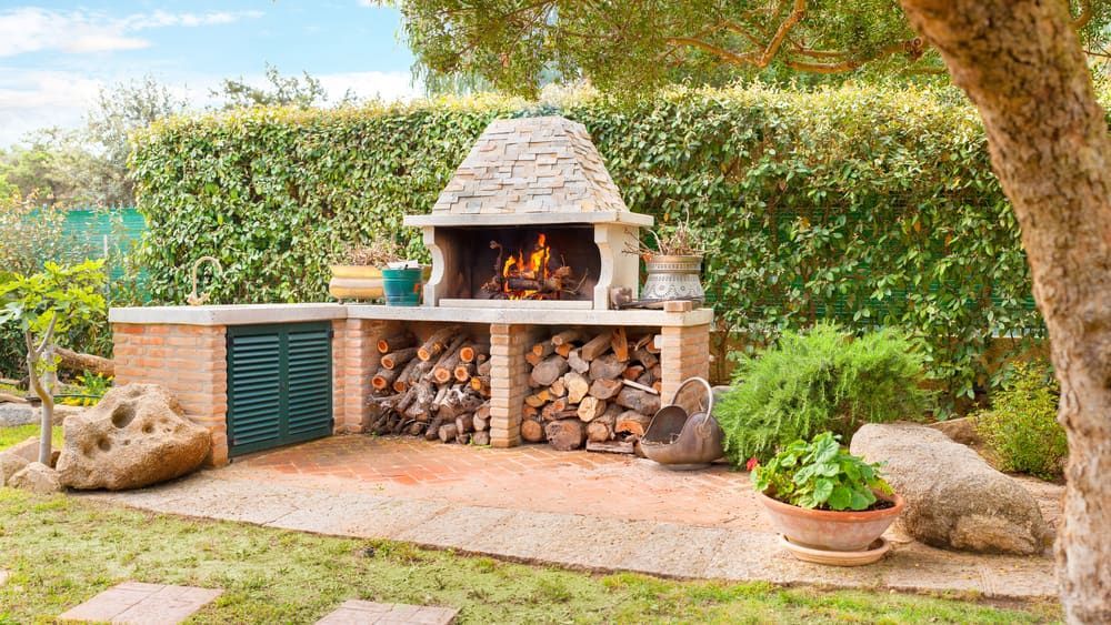 A Grill Is Sitting In The Middle Of A Garden Next To A Pile Of Wood — Serious About Landscape Supplies In West Gosford, NSW