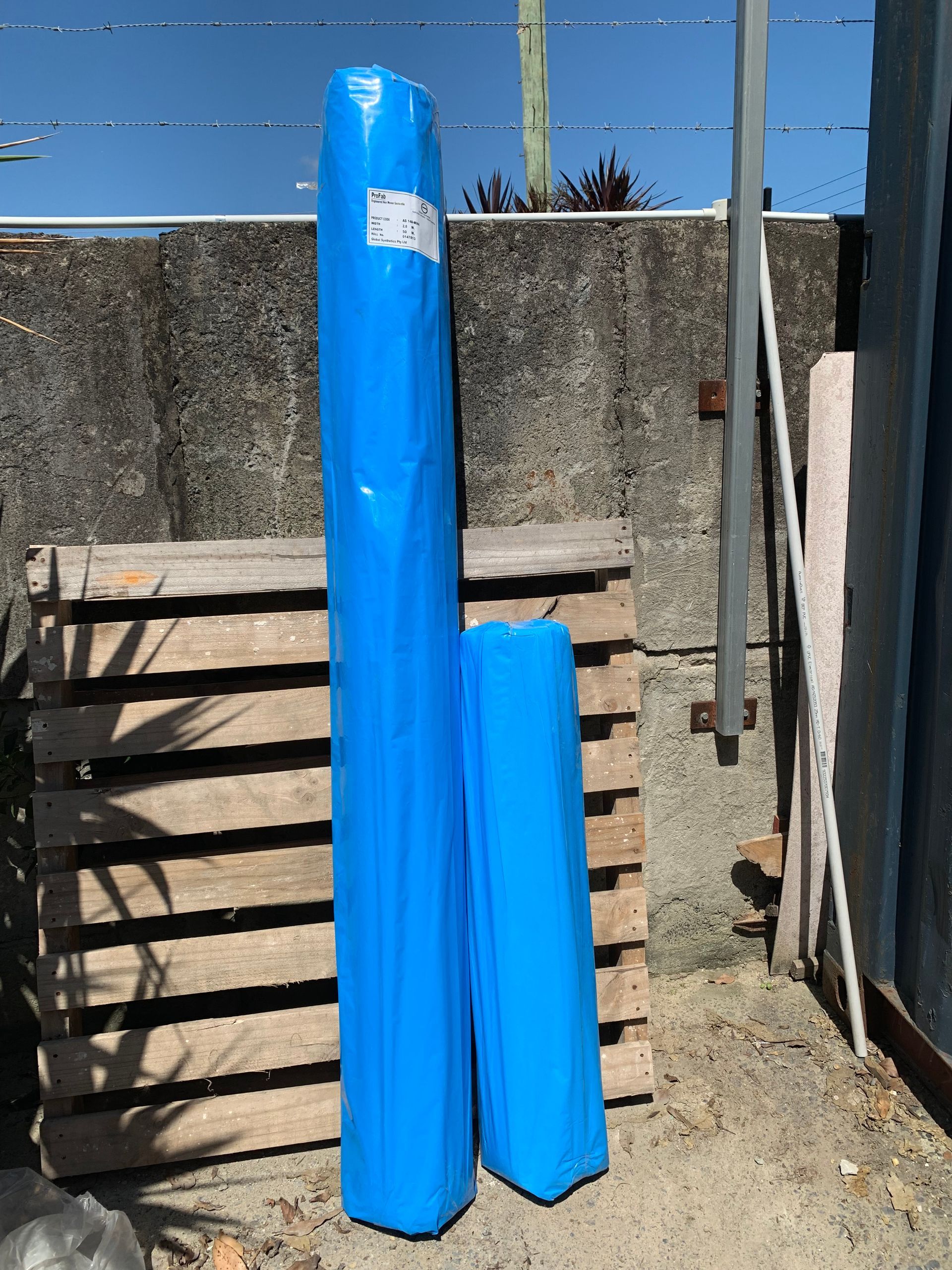2 Blue Rolls Leaning Against A Fence — Serious About Landscape Supplies In West Gosford, NSW