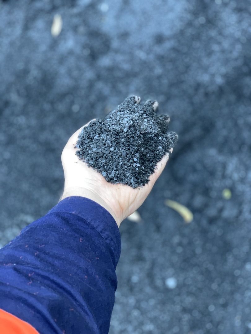 A Person Is Holding A Pile Of Black Sand In Their Hand — Serious About Landscape Supplies In West Gosford, NSW
