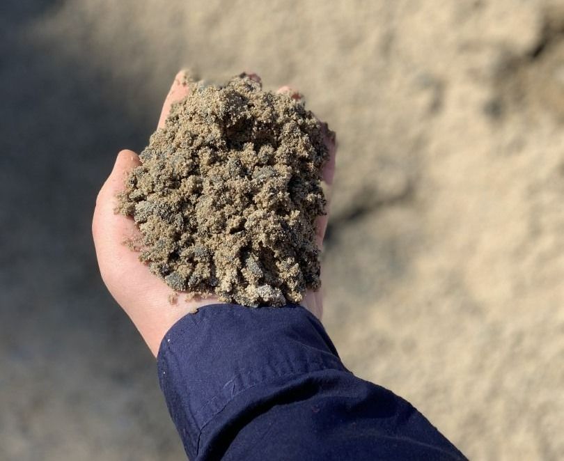 A Person Is Holding A Pile Of Dirt In Their Hand — Serious About Landscape Supplies In West Gosford, NSW