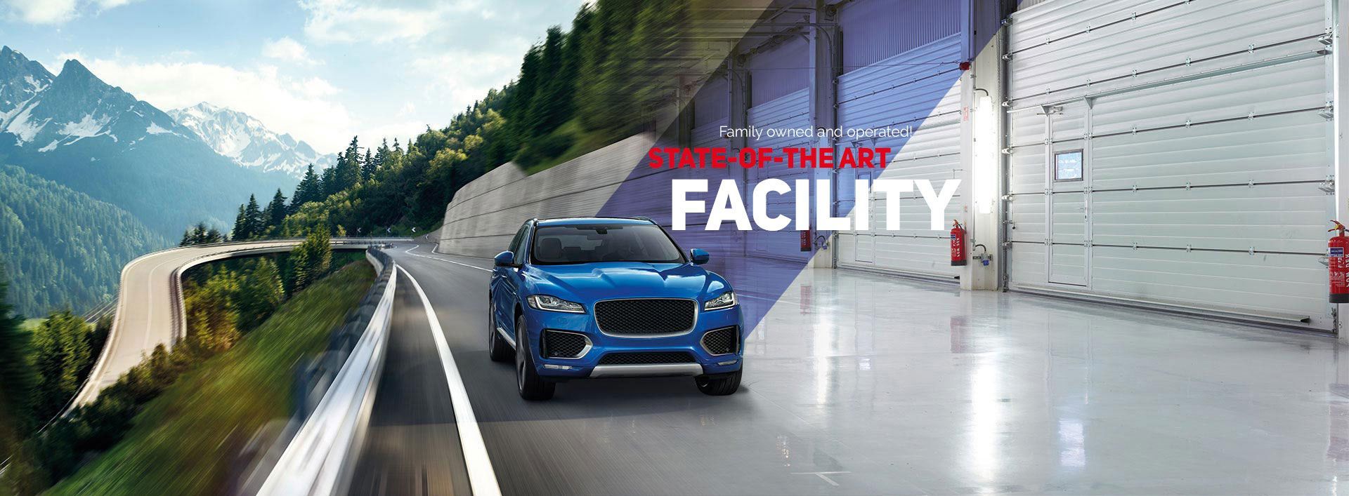 Blue SUV driving on a wet road beside a modern facility with mountains in the background | S.G. Auto Repair