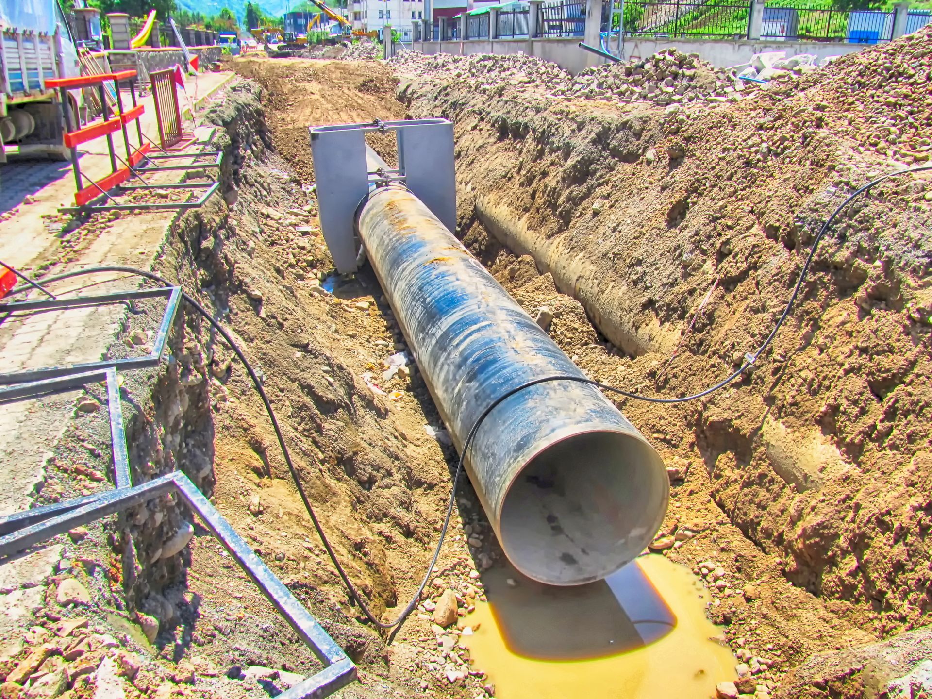Two large black pipes installed in a trench for an underground utility or water system.