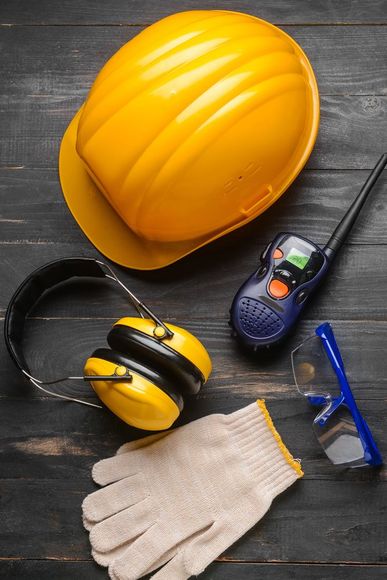 Casco amarillo, protectores auditivos, guantes de seguridad, gafas protectoras y un walkie-talkie