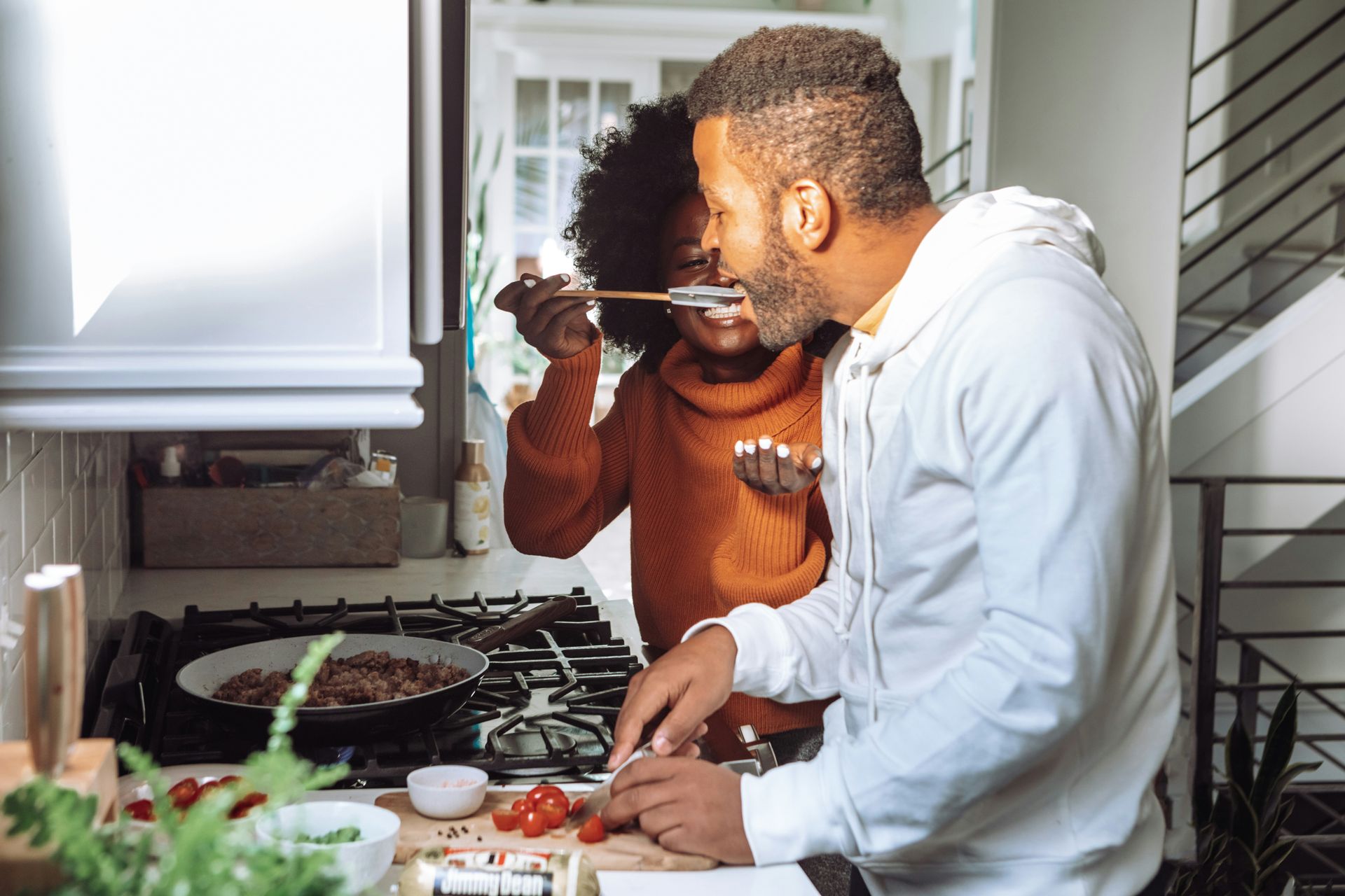 A man and a woman are cooking together in a kitchen.